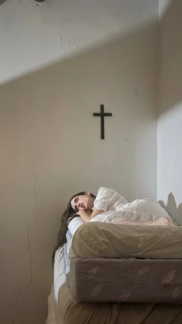 La protagonista en la cama bajo el crucifijo