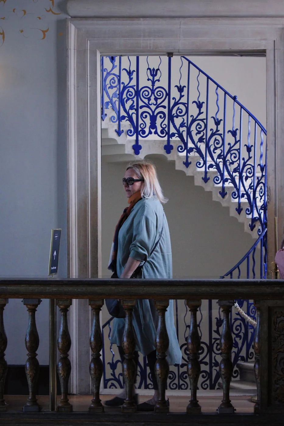 Mujer pasando ante una escalera de hierro azul