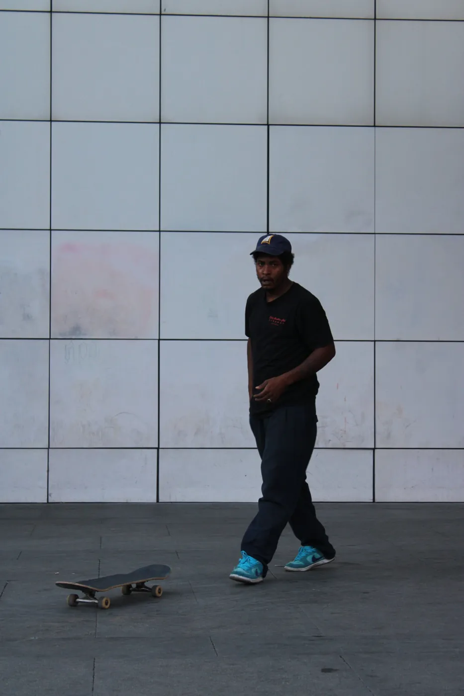 Skater caminando hacia su tabla frente a una pared de paneles