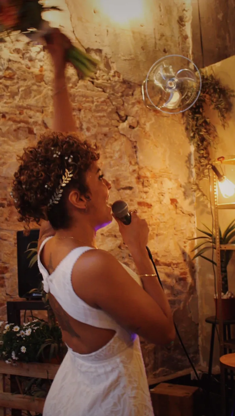 Novia cantando al micrófono con el ramo en alto