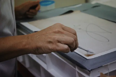 Mano restaurando una lámina de papel