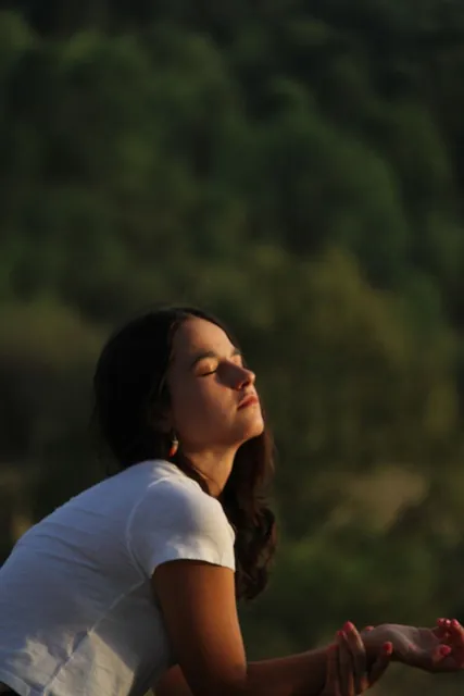 Chica con los ojos cerrados bajo la luz del atardecer