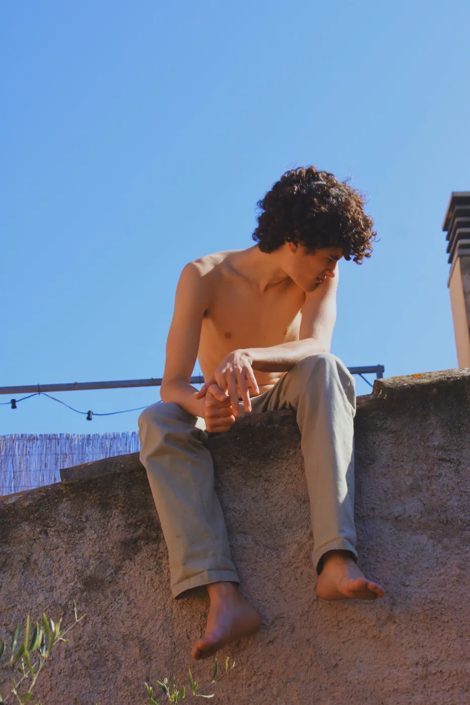 Chico sentado en un muro contra el cielo azul